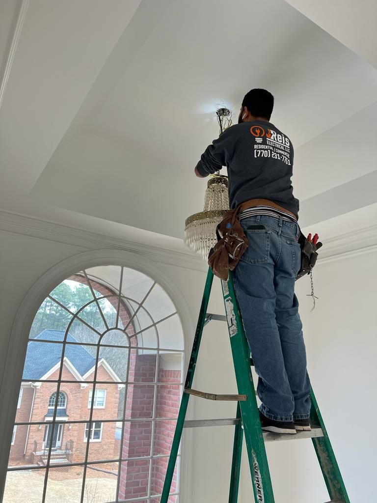 Jean Reis on a ladder installing a crystal chandelier