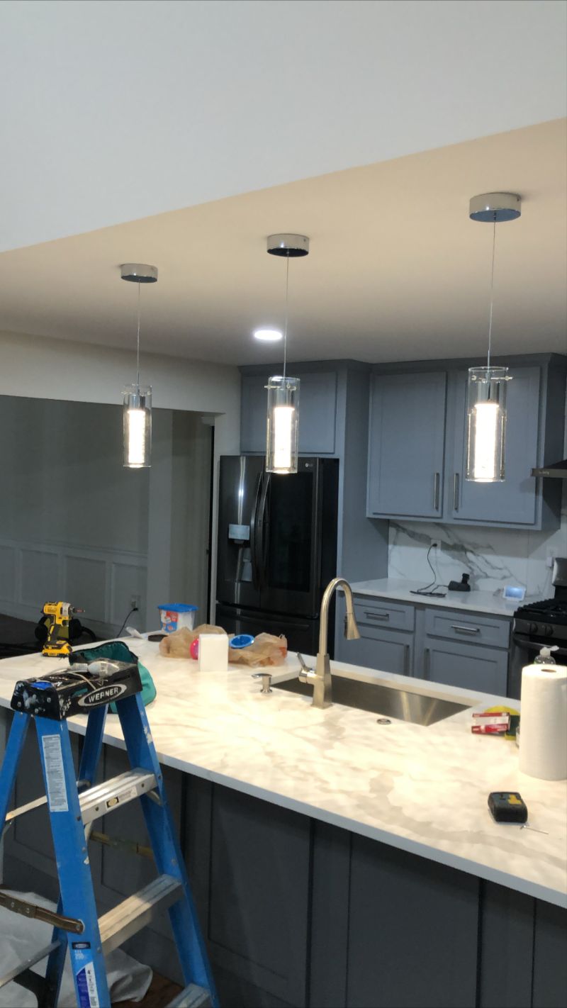 Three glass cylinder pendants over a marble kitchen island